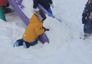 chłopcy zrzucają śnieg ze zjeżdżalni