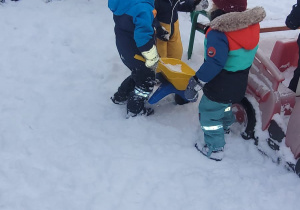 dzieci wiozą śnieg w taczkach