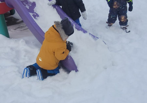 dzieci bawią się śniegiem przy zjeżdżalni