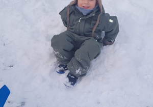 chłopiec siedzi na śniegu