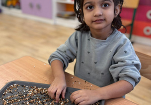 dziecwczynka robi z ziarna kolbę dla ptaków
