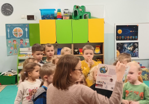 Dzieci z zaciekawieniem słuchają książki.