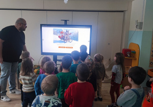 Dzieci stoją przed tablicą multimedialną