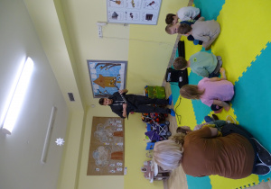 Dzieci słuchają gry na gitarze elektrycznej.