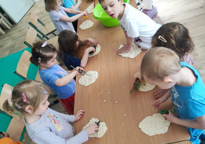 Odciskanie śladów dinozaurów przez dzieci.