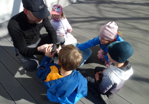 pan z serwisu rowerowego tłumaczy dzieciom w jaki sposób napompować dętkę