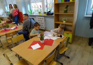 chłopcy siedzą i jedzą ciasto