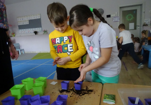 dziewczynka wsypuje nasiona do doniczki