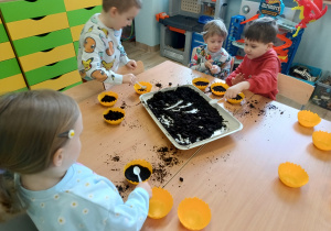 Dzieci wypełniają doniczki ziemią