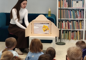 Bratki siedzą na dywanie i oglądają teatrzyk