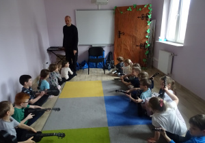 dzieci siedzą i grają na ukulele
