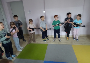 dzieci stoją i grają na ukulele