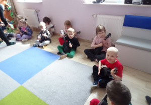 dzieci siedzą i grają na ukulele