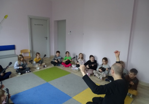 dzieci siedzą i grają na ukulele