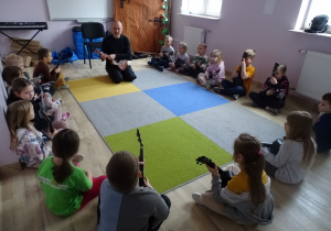 dzieci siedzą i grają na ukulele