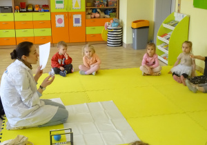 Prowadząca zajęcia pokazuje dzieciom kartki w różnej formie