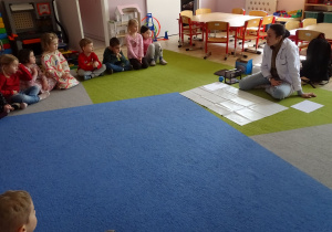 dzieci siedzą i patrzą na prowadzącą zajęcia