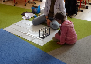 dziewczynka wprawia w ruch wahadło Newtona