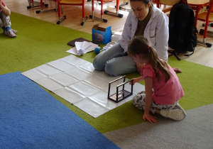 dziewczynka wprawia w ruch wahadło Newtona