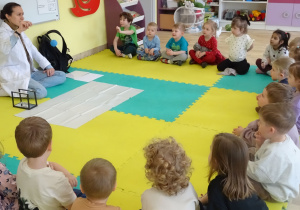 dzieci siedzą i patrzą na prowadzącą zajęcia
