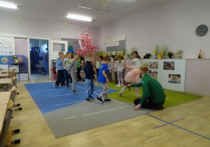 dzieci przeskakują nad trzymanym przez trenera przyrządem gimnastycznym