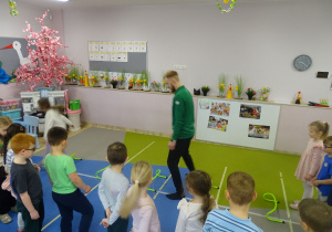 trener prezentuje dzieciom w jaki sposób pokonać tor przeszkód