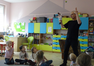 dzieci siedzą i patrzą na aktora, który ma pacynkę i opowiada w jaki sposób się ją nakłada na ręke