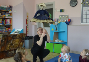 Pan Paweł pokazuje z dziećmi jak poruszać kukłą