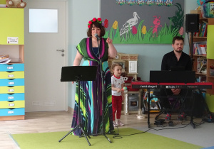 Artystka w kolorowej sukience stoi na scenie