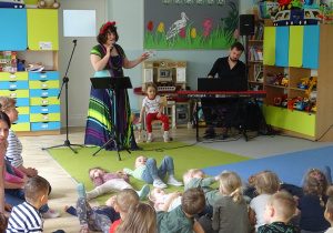 Dzieci siedzą na dywanie i słuchają piosenek