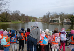 Nauczyciel pokazuje dzieciom w oddali Pałac na Wyspie