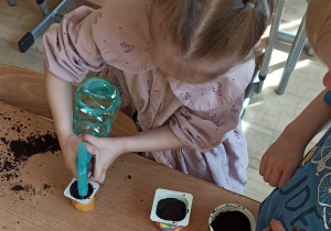 Dzieci przygotowują doniczki do sadzenia roślin