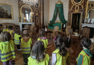 Dzieci zwiedzają komnaty z przewodnikiem.