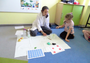 dziewczynka patrzy na przedmiot w misce z wodą