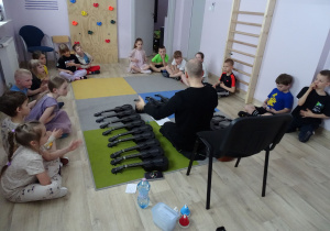 dzieci siedzą na podłodze i słuchają pana Michała