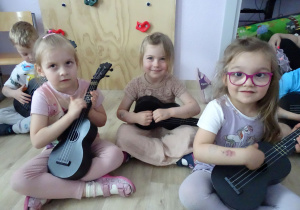 dziewczynki siedzą i trzymają ukulele