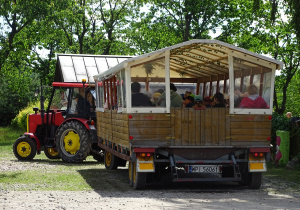 Dzieci siedzą w wozie ciągniętym przez traktor