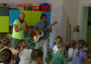 Dzieci tańczą do muzyki granej na żywo na flecie i gitarze