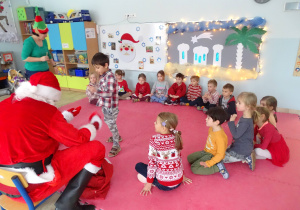 Mikołaj rozdaje dzieciom prezenty.