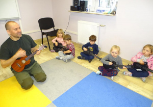 Pan Michał uczy dzieci grać na ukulele
